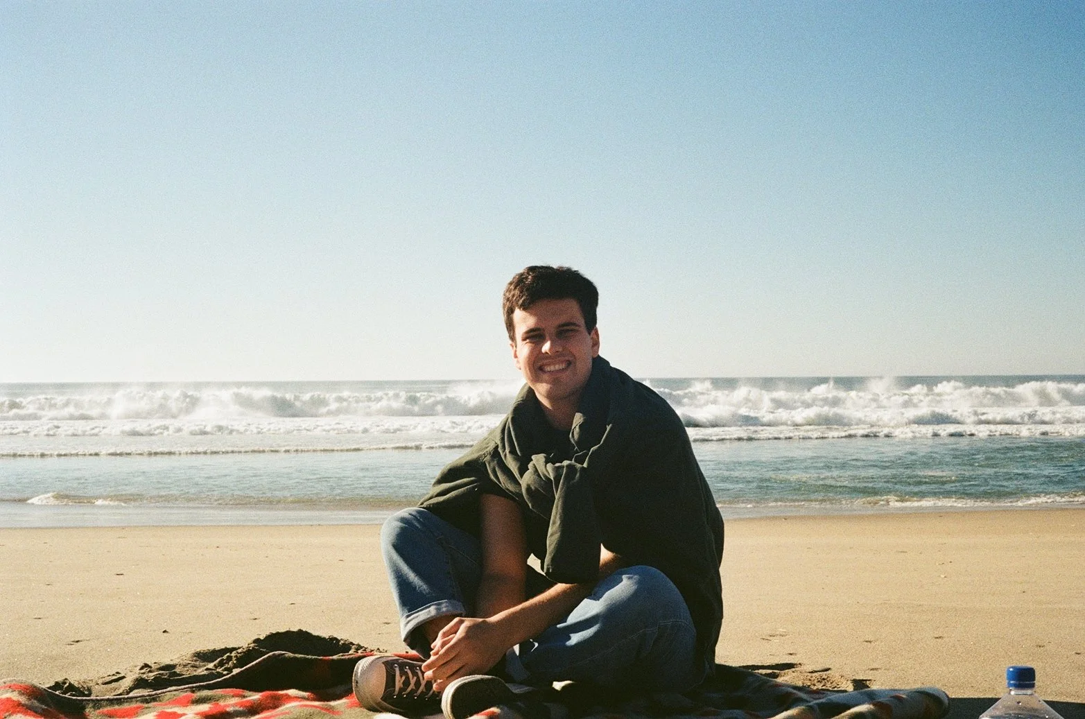 Charlie sitting on a blanket at the beach
